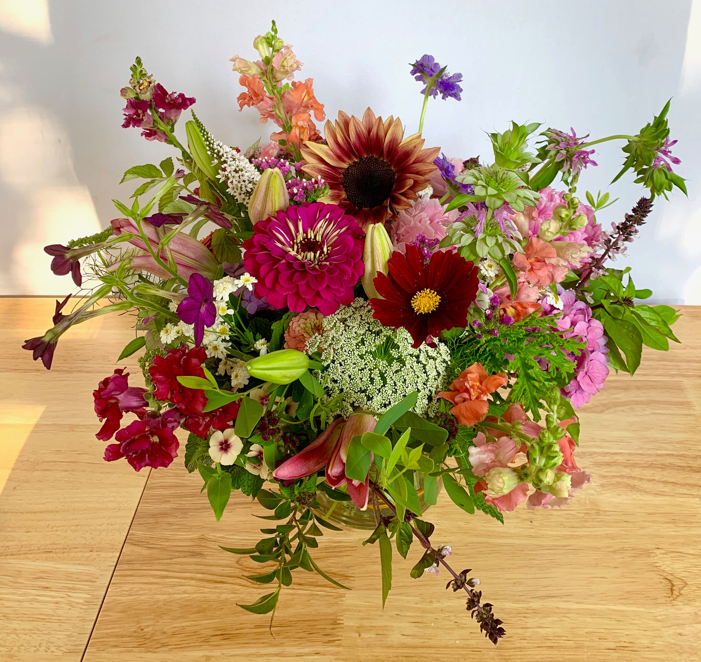 Colorful flower arrangement on a wooden surface with a light background