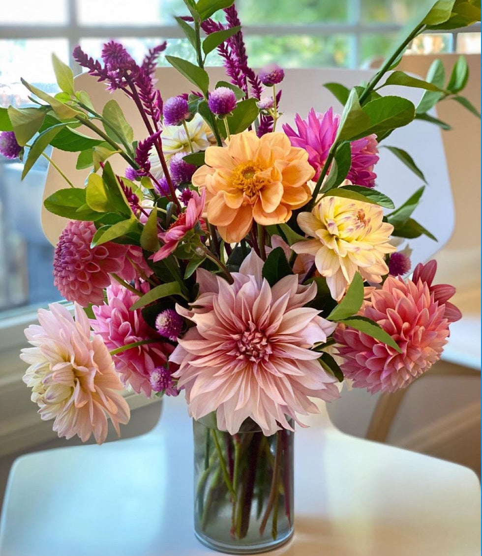 Colorful flower arrangement in a vase on a table with a blue border and text overlay.