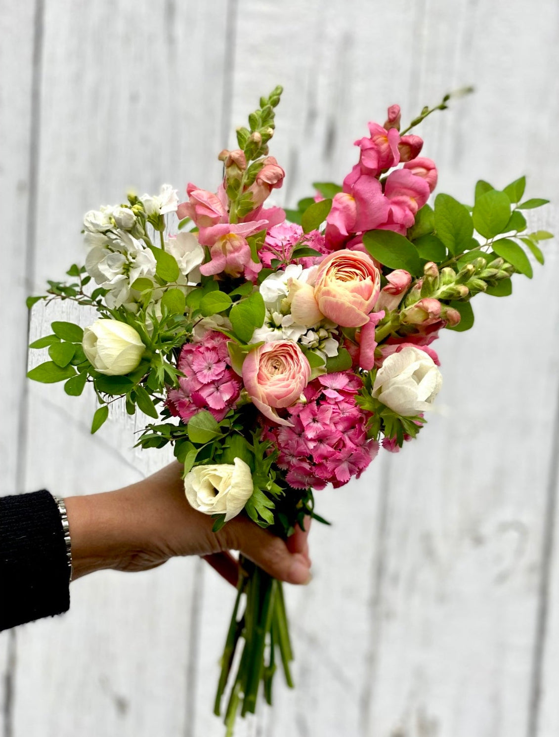 Bouquet of flowers held by a hand with a light gray background
